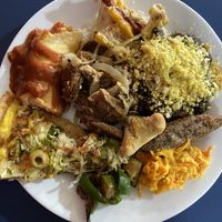 Open buffet plate: Pizza, pancake, cauliflower, rice and beans (feijoado), kibe, beef with onions, carrot salad, peppers and fried salgadinhos  at LAR vegan in Sao Paulo