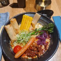 Vegan ramen: 2 veg spring rolls, corn, broccolini, baby carrot, sundried tomatoes, cherry tomato, *pickled onions, *slices of bamboo shoot (*not sure) in creamy coconut broth. at HAV Sushi & Ramen in Tromsoe