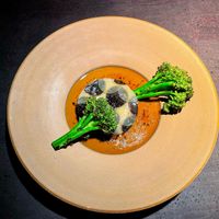 round potato slice with creamy/liquid core in a gravy sauce with truffle topping and roasted wild broccoli  at Pramerl & the Wolf in Vienna