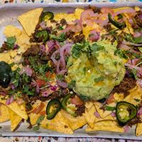 Loaded nachos, hand for scale at Club Mexicana - Boxhall City in London