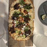 Pastrami & Charred Tomato Flatbread

Flatbread with ricotta, mozzarella, pulled pastrami, charred cherry tomatoes, habanero sauce, cilantro, avocado mouse and crumbled feta.  at Reverie Restaurant and Cocktail Bar in Brooklyn