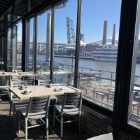 Interior seating with a view of the river, and patio seating outside at Collision Bend Brewing Company Cleveland in Cleveland
