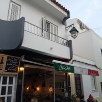 The front of the building advertising gluten free and vegan pasta, pizza and desserts at Trattoria L'Allegria in Alvor
