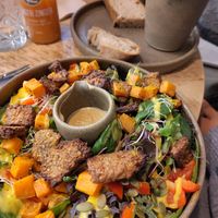 Warm mango dressing tempeh pumpkin salad with tahini sauce at Plant Shack in London