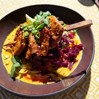 Peanut-orange marinated soy skewers in a slightly spicy curry sauce with rice noodles and red cabbage kimchi at Vegan Restoran V in Tallinn