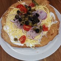 Lángos with vegan sour-cream,  vegan cheese, red onion,  olives (black and green), tomato at Retro Lángos Budapest Vécsey 3 in Budapest