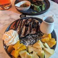 Pancakes with fruit, without roasted nuts, syrup in the jug. Chicken bagel at Bubita Bar in Barcelona