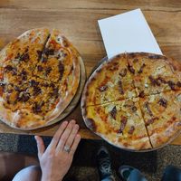 these are two small pizzas, hand is just there for the size reference. vegan tuna is love! at Hatool HaYarok - The Green Cat in Tel Aviv