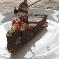 Slice of raw avocado and chocolate tart, garnished with pomegranate seeds at Moehren Milieu Eco Cafe in Mainz