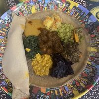 Vegetarian mix - potatoes, green peas, green beans with carrot, green lentils, purple cabbage, yellow peas, spinach, pea puree from top clockwise. Soy chunks in spicy sauce middle  at Habesha 2 Restaurant in Emilia-romagna