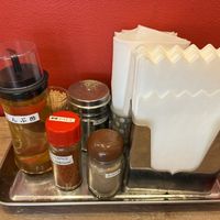 Condiments, napkins, and paper aprons  at ANDRYU★ - らーめん薬膳担々麺　アンドリュー★ in Osaka
