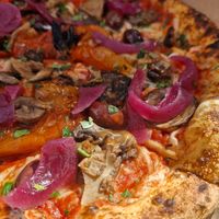 Neapolitan pizza with mushrooms, bell peppers, sweet onion, fresh olives and tomatoes and vegan cheese. Drizzled with garlic oil and sprinkled with parsley at Semo. Italian Street Kitchen  in Copenhagen