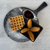 Crispy, golden plant-based chick'n served over a fluffy french vanilla waffle, drizzled with maple syrup and a touch of vegan butter for the perfect sweet-and- savory classic. at Aisha's Plant-Based Eatery in Miami