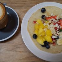 Oat milk latte and pancake with fresh fruit and extra nuts - lovely light breakfast at Kin Cafe Vegetarian in London