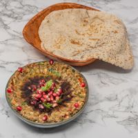 Smoky roasted aubergine blended with tahini and spices, served with warm Arabic bread. A classic Syrian vegan dip. at Damastique in York