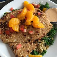 Bikini Bowl

Quinoa over a bed or garlic steamed greens, topped with mandarin oranges, diced tomatoes, and a grilled citrus-marinated tempeh cutlet. Served with a side of chipotle-tahini dressing at The Wayward Cafe in Seattle