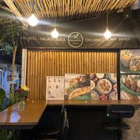 This is the type of seating that they have and you can see people passing by  at Falafel Warung in 