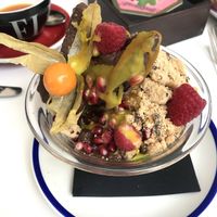 Açaítella bowl €8.95. Kiwi and banana on bottom covered with açaí, pomegranate, raspberries, brazil nuts, turmeric glaze at Flax & Kale - Placa Castella in Barcelona