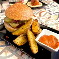 Hamburguesa casera de soja y remolacha con "cheddar", encurtidos
y mayo siracha en pan de semillas con patatas asadas y salsa BBQ  at VEGA - Luna in Madrid