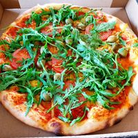Pizza with vegan cheese, rocket, fresh tomatoes and olives at Fleischfrei in Dusseldorf