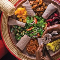 The owner showing how to begin eating with spongy injera. Photo by @TorontoLife at Selam in Toronto