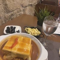 The francesinhas with fries, plus seasoned olive starter  at Francesinhas Al Forno da Baixa in Porto