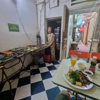 75 year old matron stands proudly by the buffet at Tu Hao in Hanoi
