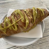 Vegan plain croissant stuffed and drizzled with pistachio cream. You can also buy jars of the pistacchio cream.   at Feliz Cafe in Peschiera Del Garda