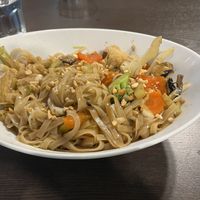 Pad thai. Flat rice noodles with tofu and veg. Topped with peanut pieces. Served in a curved oval bowl    at Veggo Sizzle in Adelaide