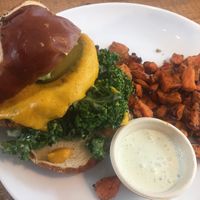 Cited “Best Veggie Burger in America” superfood patty, plantbased cheddar, homemade guacamole, marinated kale, cilantro aioli with sweet potato fries at Love Life Cafe in Miami
