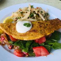 savory chickpea pancake stuffed with smoked tofu, fry onions and red peppers, fresh baby spinach, tomatoes, topped with plant yoghurt and served with asian cabbage salad. at One Bowl in Copenhagen