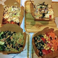 Four small salad boxes.  3 different salad choices in each on a bed of mixed 1/2 rice, 1/2 greens.  at Fresca in Hong Kong Island