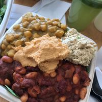 super hero sampler with bean chili, chickpea masala, veggie tuna, black bean ball on a bed of spinach and quinoa. green advanced juice on the side at Plant Wise in Dix Hills