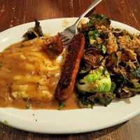 Oktoberfest Plate. Oven roasted Beyond sausage, served with mashed potato, sauerkraut and brussel sprouts. Topped with onion gravy. at Veg Cafe in Sacramento