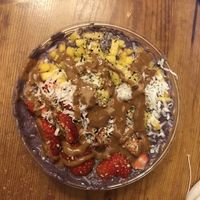 Blue almond smoothie bowl with strawberries, mangos, hemp seeds, and coconut toppings and almond butter drizzle at Dulce Vida in Hanover Park