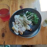 small plate of batata (sweet potato) with cashew lebaneh, tabuleh and tofu. on the left there's hybiscus lemonade and on the right there's a shot of green soup made of mangold at Herzog in Tel Aviv