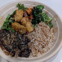 Brown ride fresh greens base, sweet potato, sesame broccoli, black beans sofrito, toasted coconut, corn fritters with ginger tamari gold sauce at Della Bowls in Miami