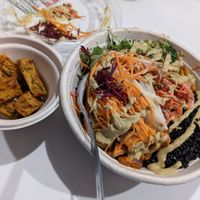 Side of corn fritters, fresh greens, black coconut rice base, sweet potato, sesame broccoli, black eyed pea tempeh, raw root vegetables, spicy slaw with coconut curry sauce. at Della Bowls in Miami