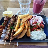 Souvlaki on plate with red smoothie. at Veganaki in Athens