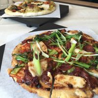 Pizza in front is the Kim Jack-Il with
Hoisin Crema, Cashew Mozzarella, Kimchi, Gochujang Braised Jackfruit, Roast Brocollini and Scallion.
Pizza in the back is the Ultraviolet with walnut Pesto, Cashew Mozzarella, Oven Dried Tomatoes, Purple Kale, Caramelized Onion and Pine Nuts.

 at Virtuous Pie  in Vancouver