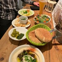 Counter-clockwise: Avocado hummus, garlic and date dip, schug (with pickles), mushroom hummus, pita, and friends salad at Hummus & Friends in Berlin