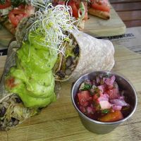 BLACK BEAN & BROWN RICE BURRITOS
onions, green chiles and raw cashew vegan cheese sauce. Served with pico de gallo and homemade guacamole  at Holi Vegan Kitchen in North Miami Beach