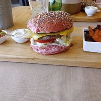Bean burger on a very narrow piece of wood, with tiny portion of vegetable crisps 😂 at Earth Shop and Cafe in Carvoeiro