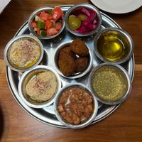 The amazing Futur Medley (all vegan). Counter-clockwise: Babaganoush, Hummus, Foule, Za'tar, EVOO, olives and (home made) pickles, cucumber-tomato salad, and falafel on center. at Ziatun in Beacon