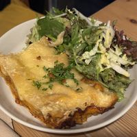 V-Lasagne Marinara mit Salatbouquet – goldbraun überbackene Lasagne mit Kräutern, daneben ein bunter Blattsalat mit Dressing auf rustikalem Holztisch  at Ich Bin So Frey in Landau