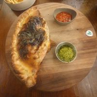 Meatless meatballs calzone: A folded pizza filled with meatless 'meatballs', vegan MozzaRisella, red peppers, calabrese sauce, pesto, olives, spinach & garlic. at Zizzi - Trafford Centre in Manchester