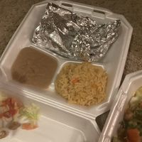 One unwrapped gordita, yummy rice and beans, and empty foil from gordita being eaten   at El Palote Panaderia in Dallas
