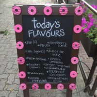 Sandwich board on street listing daily flavours (those marked "v" are the vegan options). at Oh Doughnuts in Winnipeg