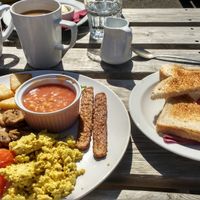 Tempeh bacon, mini hash browns, wilted spinach, scrambled tofu, black pudding (!), baked beans, sausage, mushrooms, tomatoes, toast and coffee with oat milk!!!! at Plant by Kat's Kitchen in Keswick
