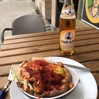 Delicious kumpir with couscous, mushrooms, chickpeas, shredded cabbage, spicy tomato sauce, vegan butter, and a ginger-turmeric sauce on top   at KartoffelKonig in Munich